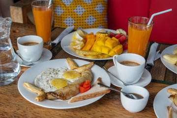 Tropical breakfast of fruit, coffee and scrambled eggs and banana pancake for two on the beach near sea