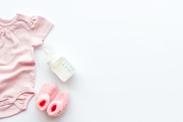 Baby background - pink color. Clothes, booties and accessories for newborn girl on white table top-down frame copy space