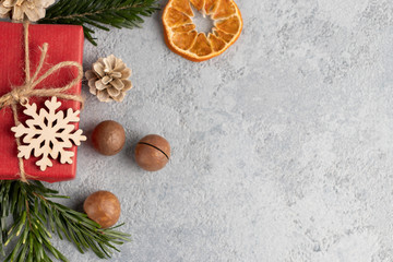 Christmas or New Year gray background with decorations from natural materials - Christmas tree twigs, nuts, cones, wooden snowflake and dried orange