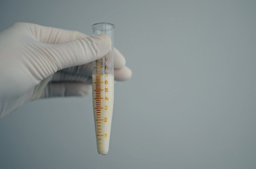 hand holding a test tube with sperm on a white background, copy spaсe 