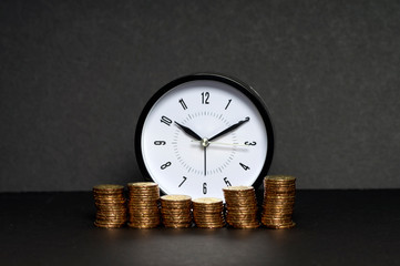 Close up of stacking gold coins and alarm clock