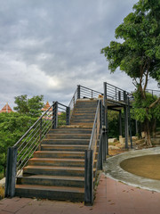 The long steel stairs up the hill in the park at the time of overcast clouds.