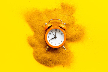 Deadline concept. Clock near sand on yellow background top-down