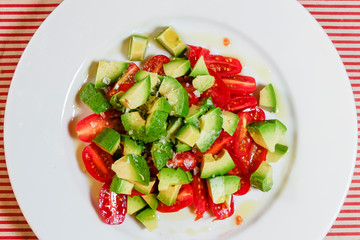 Stockholm, Sweden A tomato and avocado salad on a white plate with olive oil.