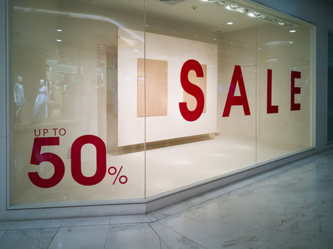 The glass display showcase has a 50 percent discount label reflecting the image of the mannequins.