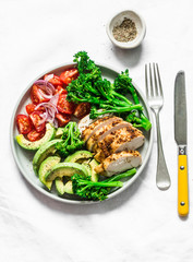 Baked chicken breast, broccoli, tomatoes, avocado salad on light background, top view. Balanced healthy eating buddha bowl