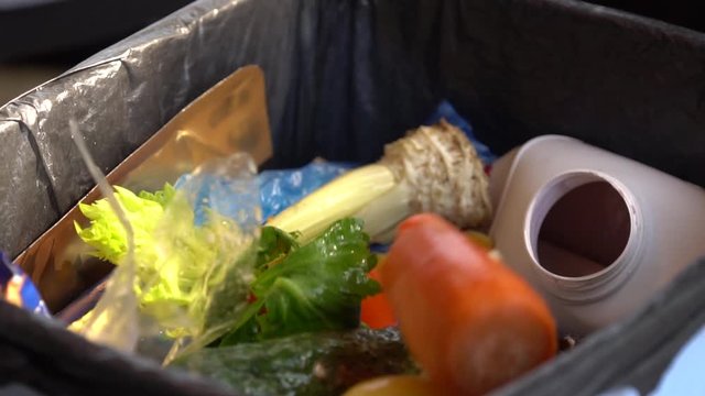 Food waste or food loss is food that is wasted, lost or uneaten. A housewife throw away perishable wasted food in trash bin