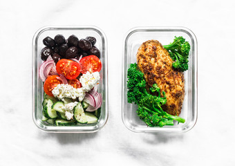Two healthy balanced lunch boxes with greek salad, baked chicken breast and broccoli on a light background, top view