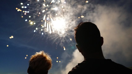 silhouette of a man looking toward fireworks