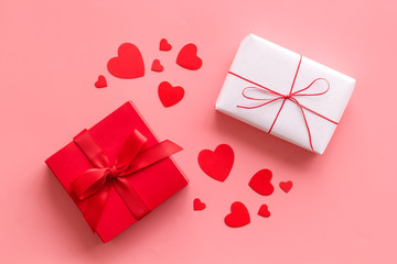 Present to a lover on Valentine's Day. Gift boxes near paper hearts on pink background top-down