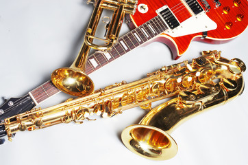 Electric guitar, trumpet and saxophone on a light background.