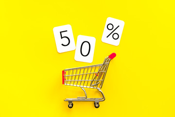 50% off discount - sale concept with shopping trolley cart - on yellow background top-down copy space
