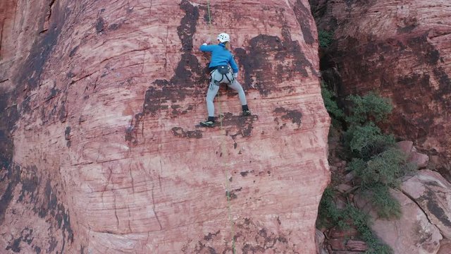 Aerial shot of female rock climber moving technically up a sandstone cliff arete