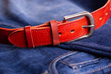 Fashionable leather belt and jeans top view. Leather belt and blue jeans close-up. Belt accessory.