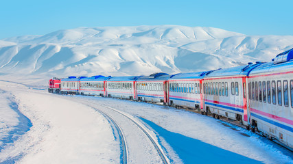 Red diesel train (East express) in motion at the snow covered railway platform - The train connecting Ankara to Kars - Turkey - obrazy, fototapety, plakaty