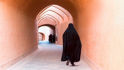 Muslim woman walking on the narrow street of old adobe Yazd city - IRAN