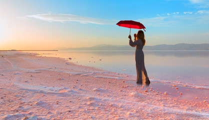 Girl with umbrella in the Maharlu pink lake at sunset - Shiraz, Iran