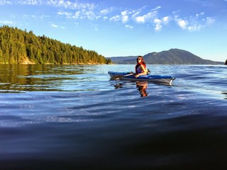 A girl enjoying kayaking on the beautiful and calm ocean waters of Howe Sound, off of Gambier...
