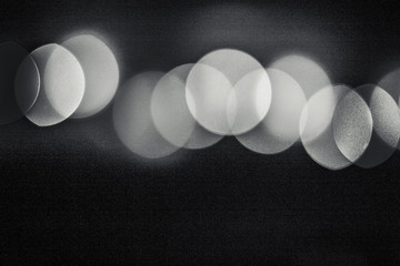Abstract unfocused background with artificial noise - black and white bokeh of different bubbles on a black background. Modern blurred pattern for design..