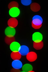 Abstract unfocused vertical background - Multi color  bokeh of different bubbles on a black background. Modern blurred pattern for design and for Christmas, New year and funny holiday backdrops..