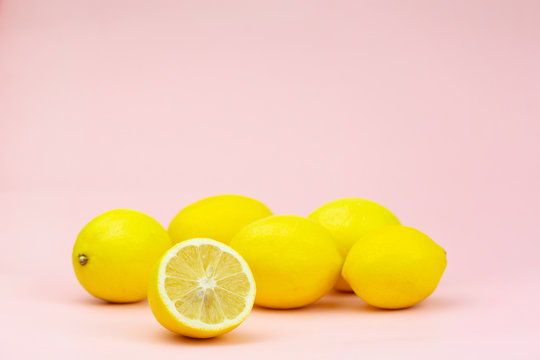 A few whole lemons and one half on a pink background with place for text