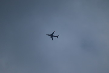 White passenger airplane in the clouds at sunset