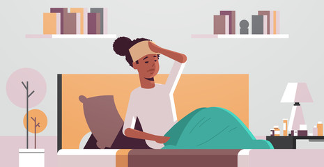 sick woman with wet towel on forehead unhealthy african american girl reducing high fever suffering from cold flu virus illness concept modern living room interior portrait horizontal vector