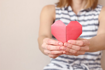 caucasian woman holding paper folded origami heart,  heart health care, insurance, charity donation concept. text area copy space, selective focus