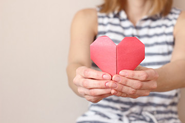 Obraz premium caucasian woman holding paper folded origami heart, heart health care, insurance, charity donation concept. text area copy space, selective focus