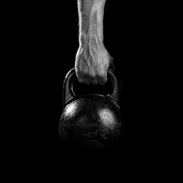 Close-up of a muscular hand holding a kettlebell. Close-up of a muscular hand holding a kettlebell. Athlete hand gripping a kettlebell.