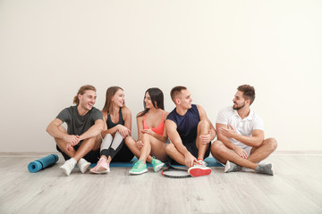 Group of sporty friends near white wall