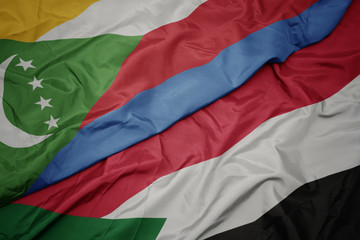 waving colorful flag of sudan and national flag of comoros.