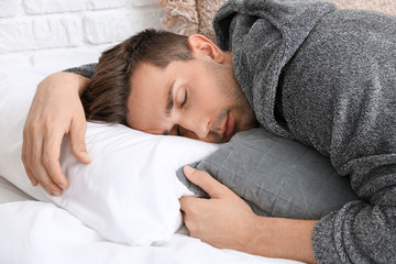 Handsome man in bathrobe sleeping on bed