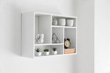 Shelf with decor hanging on white wall