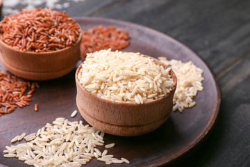 Bowls with different raw rice on wooden table