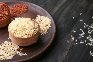Bowls with different raw rice on wooden table