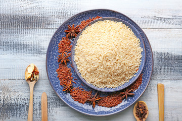 Different raw rice with spices on wooden table