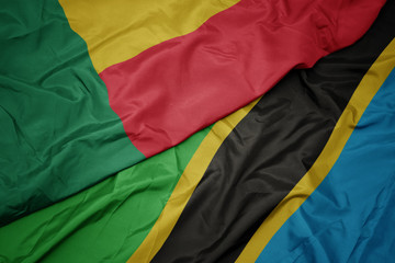 waving colorful flag of tanzania and national flag of benin.