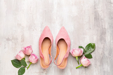 Stylish female shoes and flowers on light background