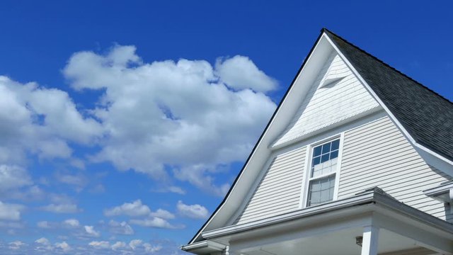 Time lapse footage of a modern house rooftop with blue sky and clouds passing by
