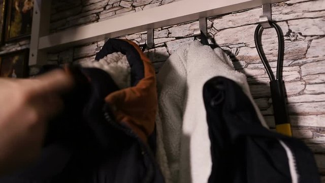 the man hangs a warm jacket on a hanger. hand close up