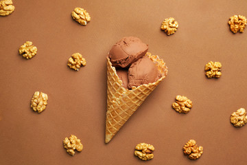 Sweet chocolate ice-cream and nuts on color background