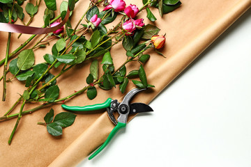 Beautiful flowers with wrapping paper and pruner on white background