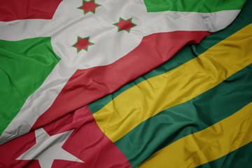 waving colorful flag of togo and national flag of burundi .