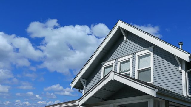 Time lapse footage of a modern house rooftop with blue sky and clouds passing by