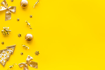 Fototapeta premium New Year card with tree, balls, present box on yellow background top-down frame copy space