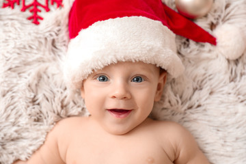 Cute little baby in Santa Claus hat lying on plaid