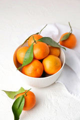 Bowl with sweet tangerines on white background