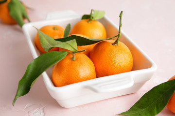 Dish with sweet tangerines on color background
