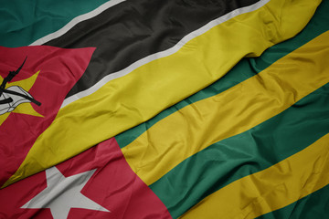 waving colorful flag of togo and national flag of mozambique.